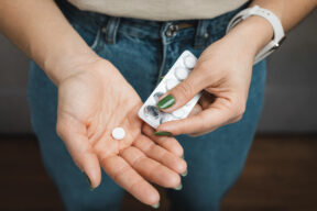 Giovane donna con una pastiglia e un blister di pillole in mano